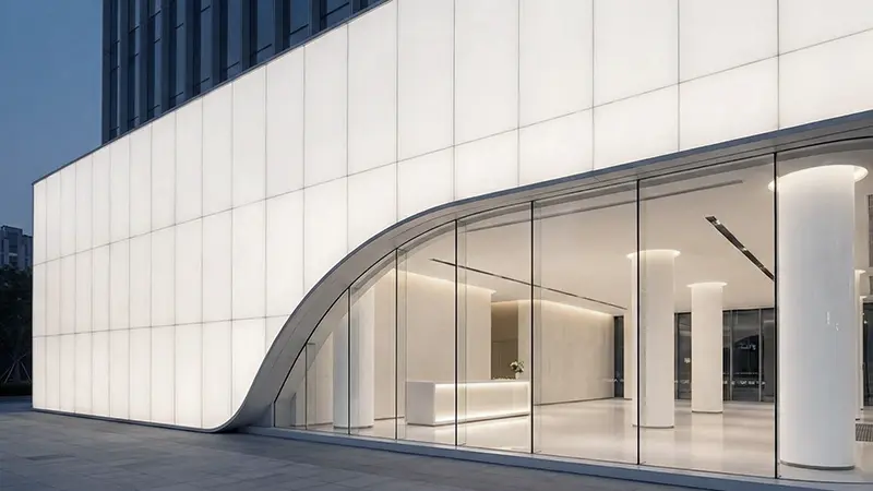 Modern architectural facade featuring ultimate pure white translucent panels with a jade-like texture and curved glass entrance.